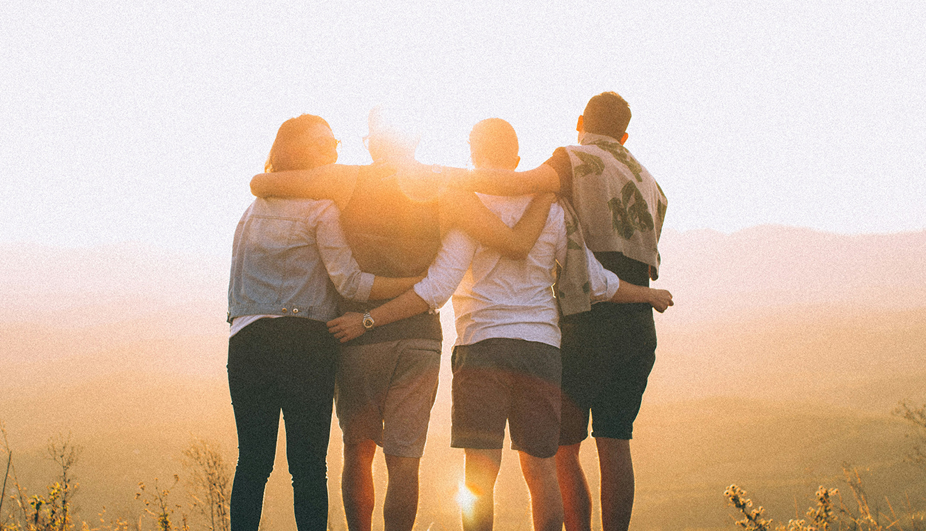 Photo of family standing arm-in-arm in front of sunset