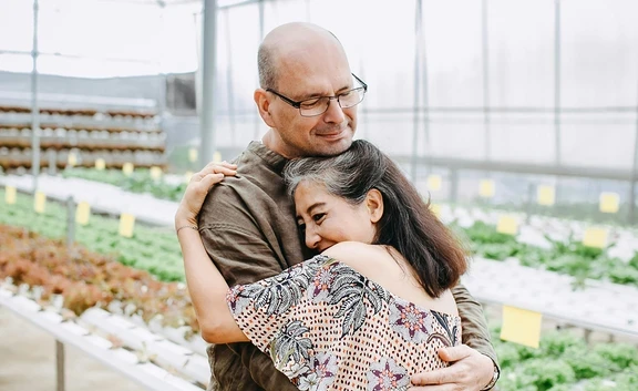 Photo of older couple hugging in a greenhouse