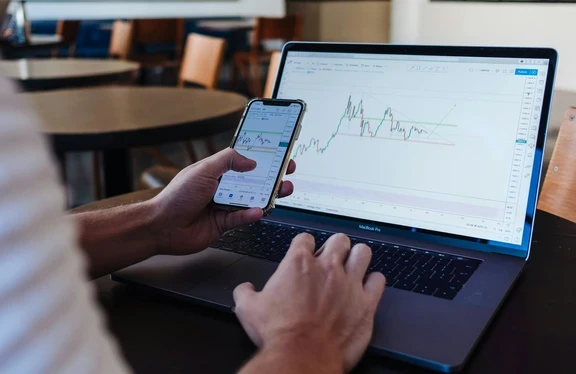 Photo of phone and computer screens displaying stocks 
