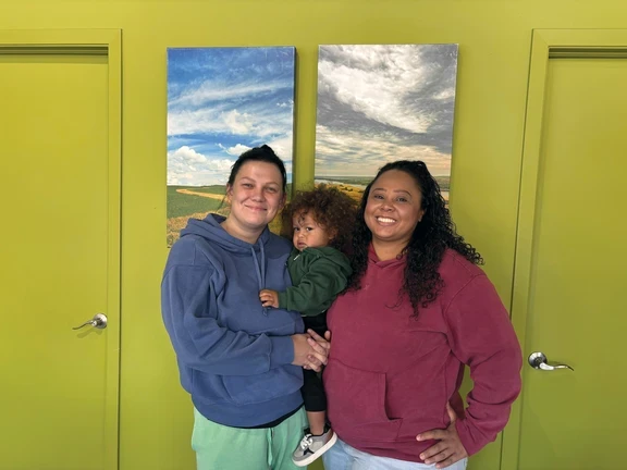 Photo of two women with toddler smiling